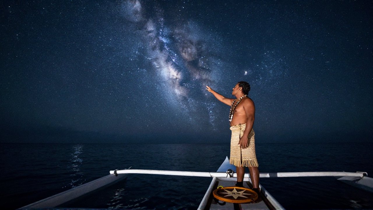 Un navegante polinesio señala las estrellas en un cielo nocturno desde su canoa tradicional.